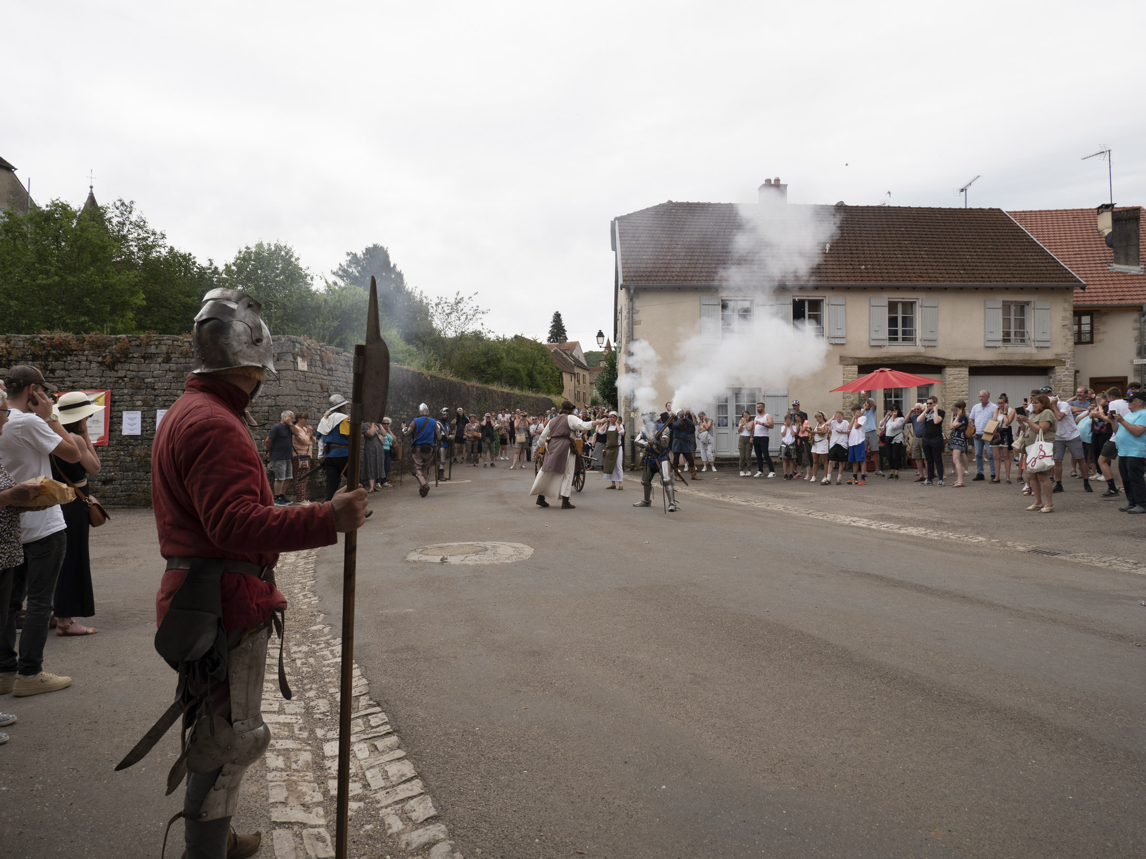 démonstration pyrotechnique dans les rues du village, avec des nombreuses spectateurs et spectatrices qui se bouchent les oreilles pour se protéger des bruits de canon