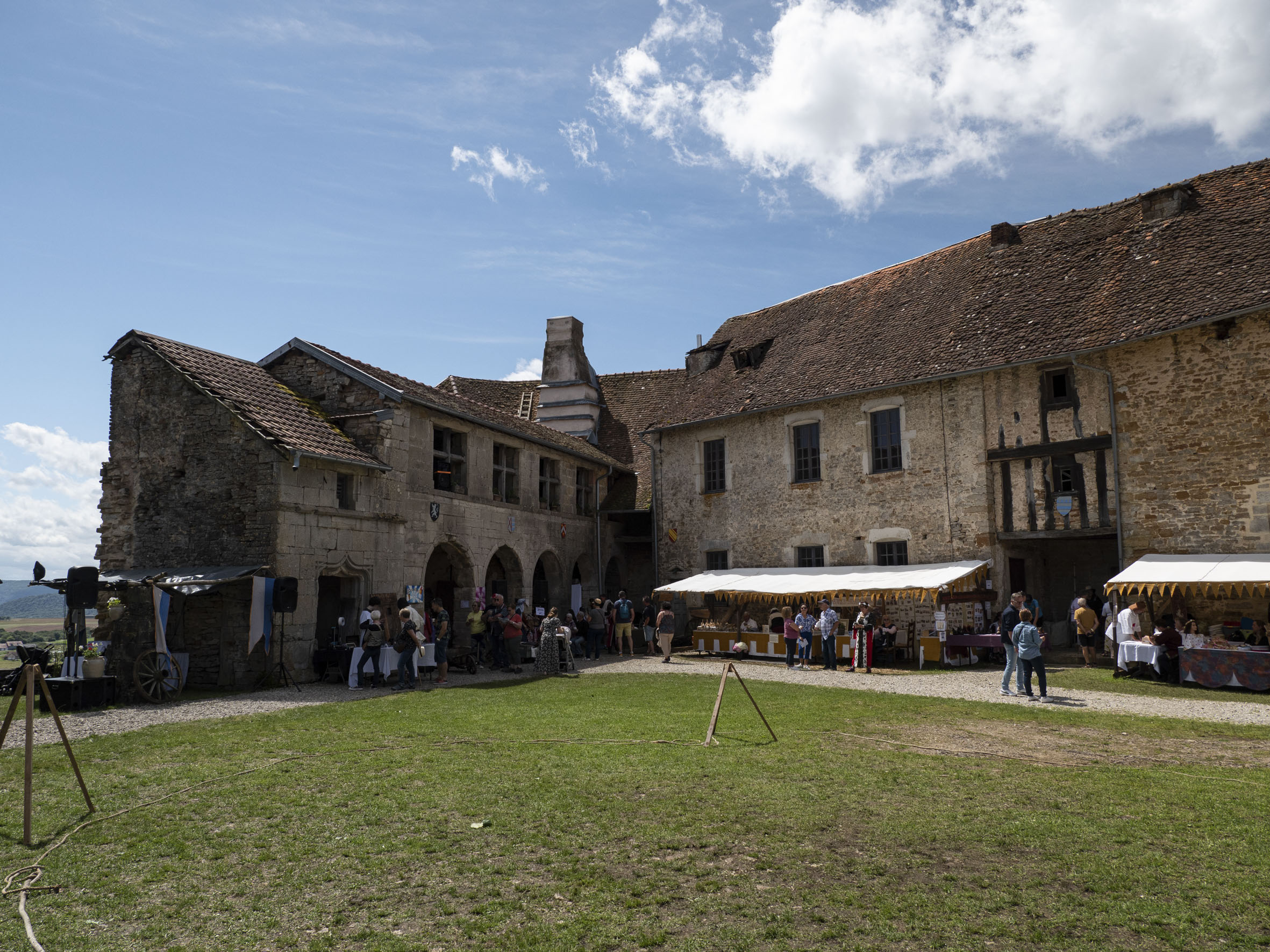 photo d'un cour enherbée devant un bâtiment en coin, devant lequel des stands sont dressés