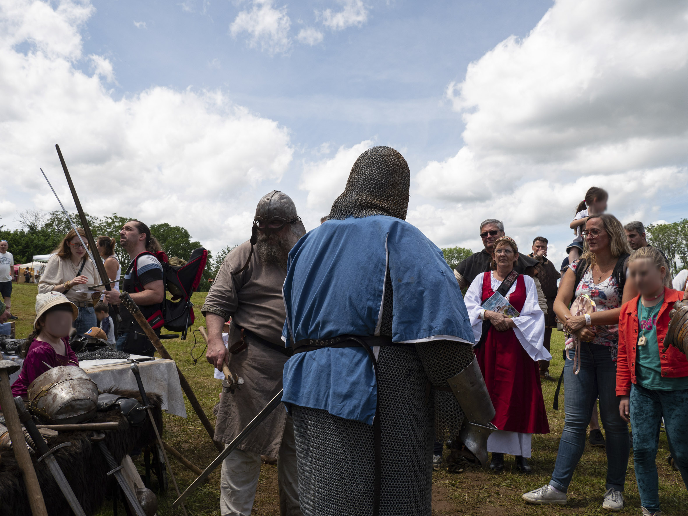 petit groupe de personnes attroupé autour d'une démonstration de combat médiéval, par deux hommes costauds en costume de chevalier, casque, cotte de mailles, épée, massette