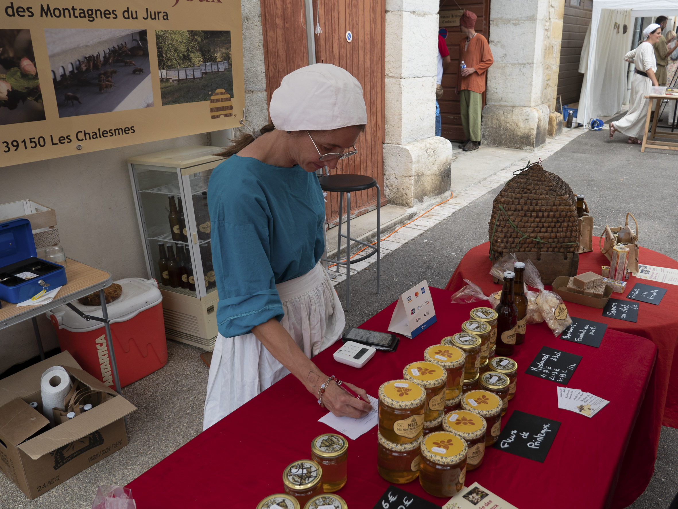 stand de vente de miel, tenu par une femme en costume de paysanne