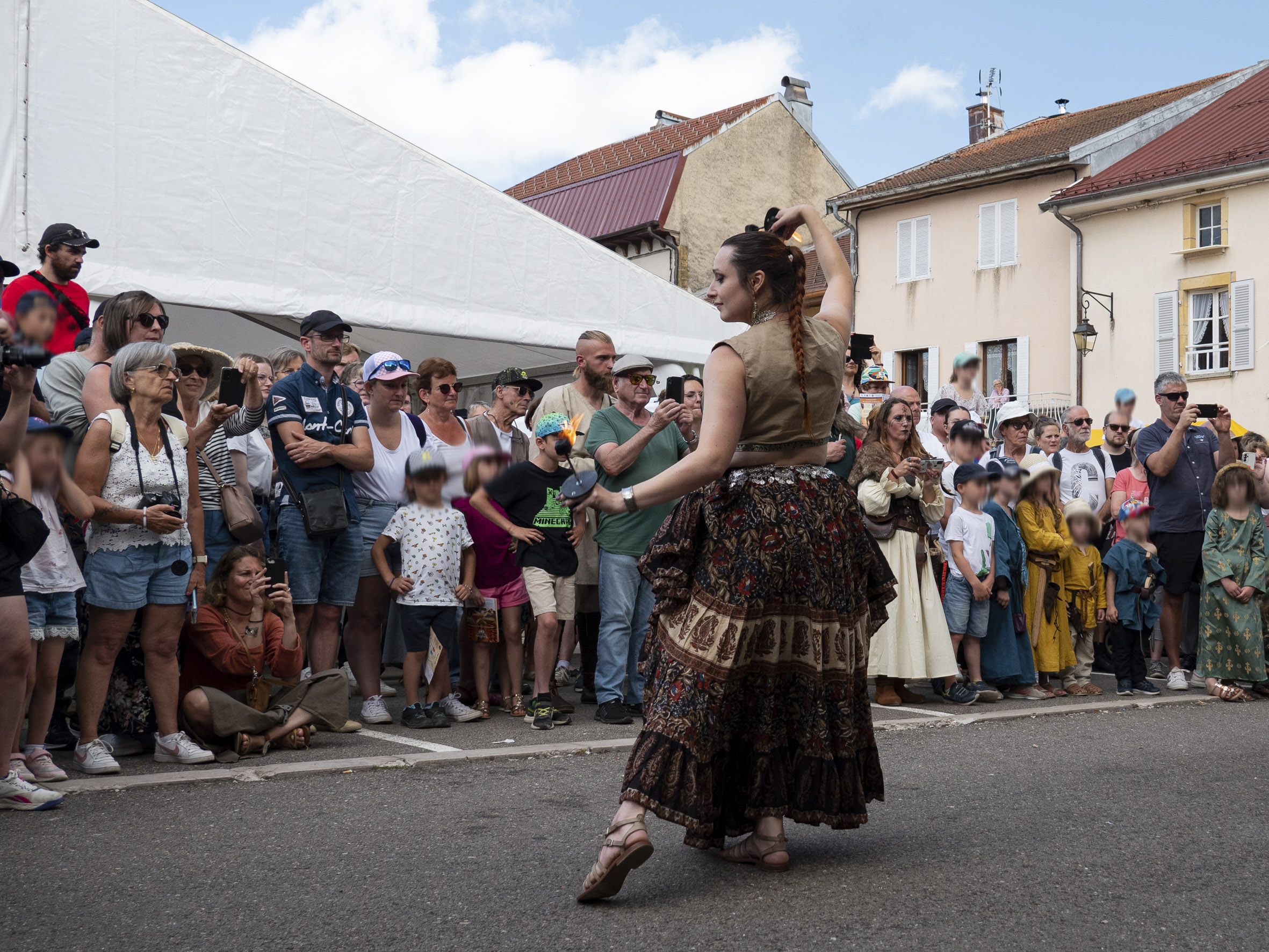 spectacle de danse dans la rue, avec une danseuse en robe devant une foule de personnes, dont de nombreux enfants