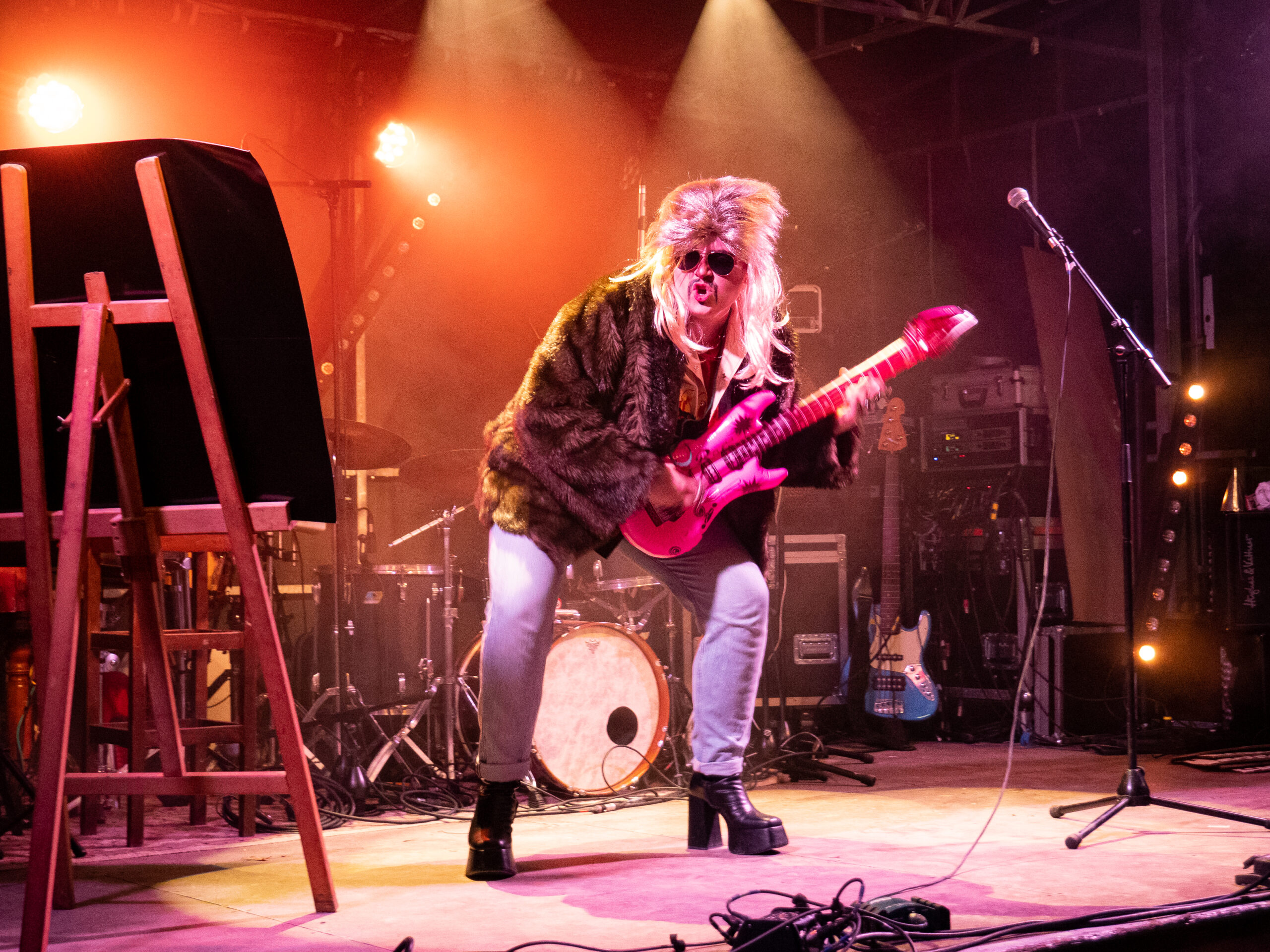 concert sur la scène de la place Granvelle, avec un chanteur playback affublé d'une perruque rose, de grosse ray ban, d'une guitare en plastique gonflable en plastique rose et de talons compensés