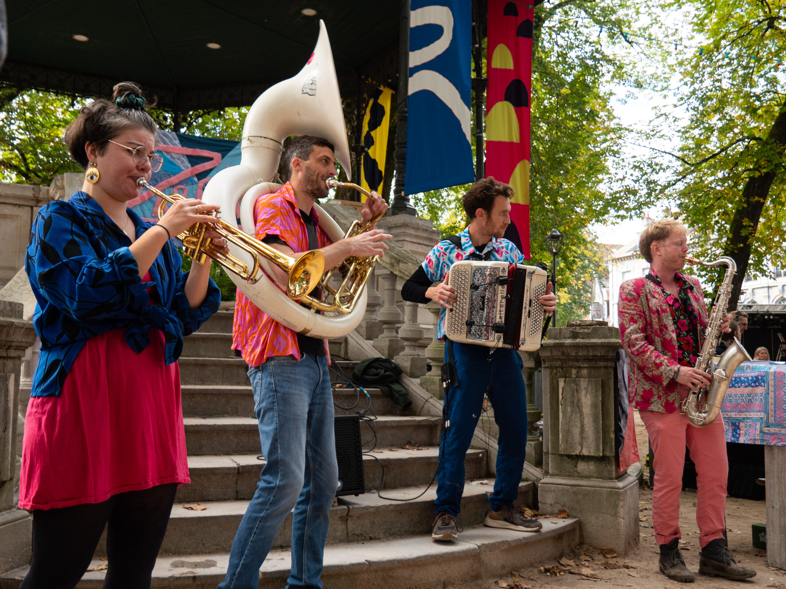 Groupe de musique jouant au bas du kiosque de Granvelle, composé d'une trompettiste, d'un tuba, d'un accordéoniste et d'un saxophoniste