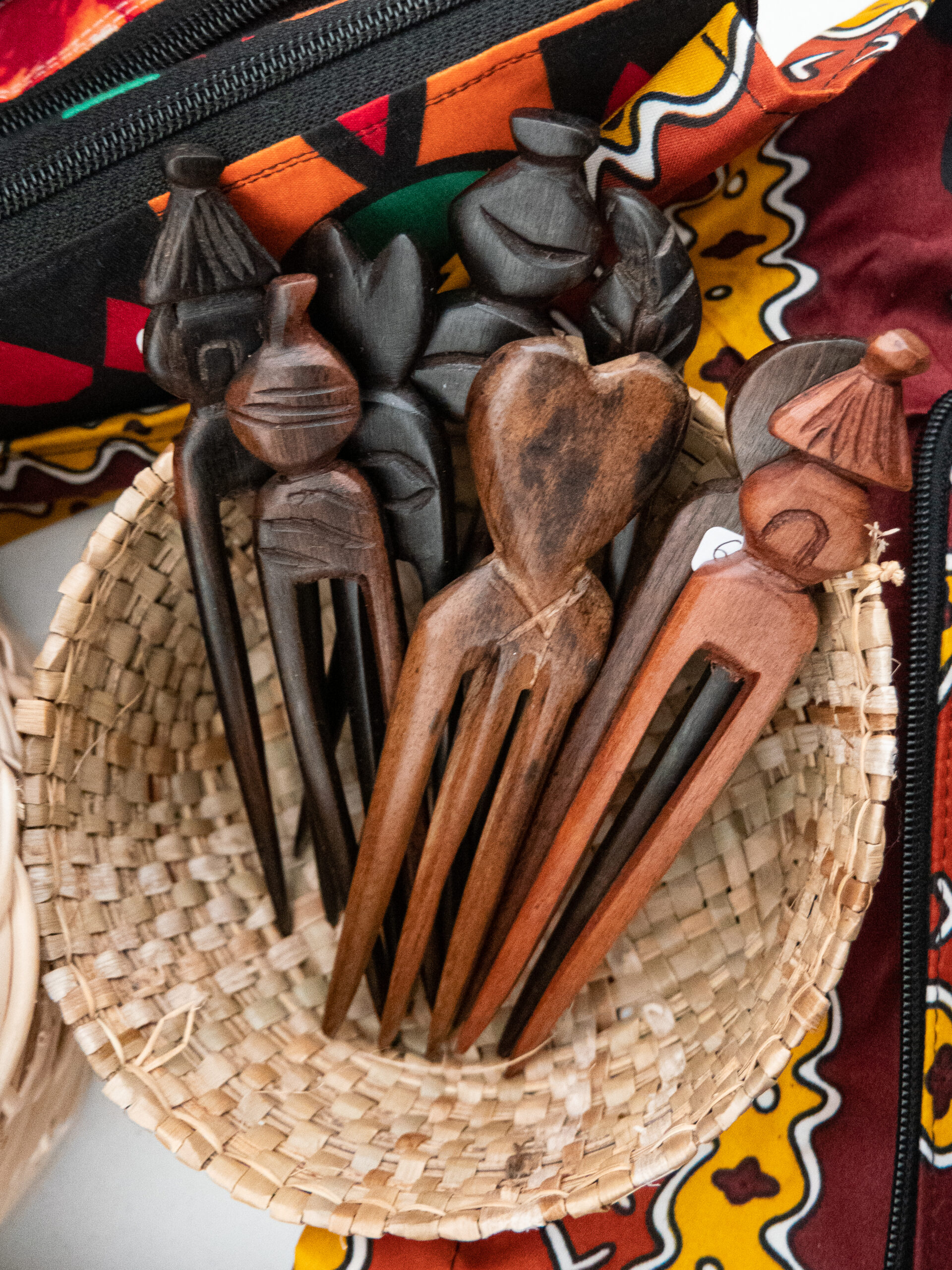 gros plan sur des broches réalisées dans du bois sombre, marron et noires, dans une corbeille en osier