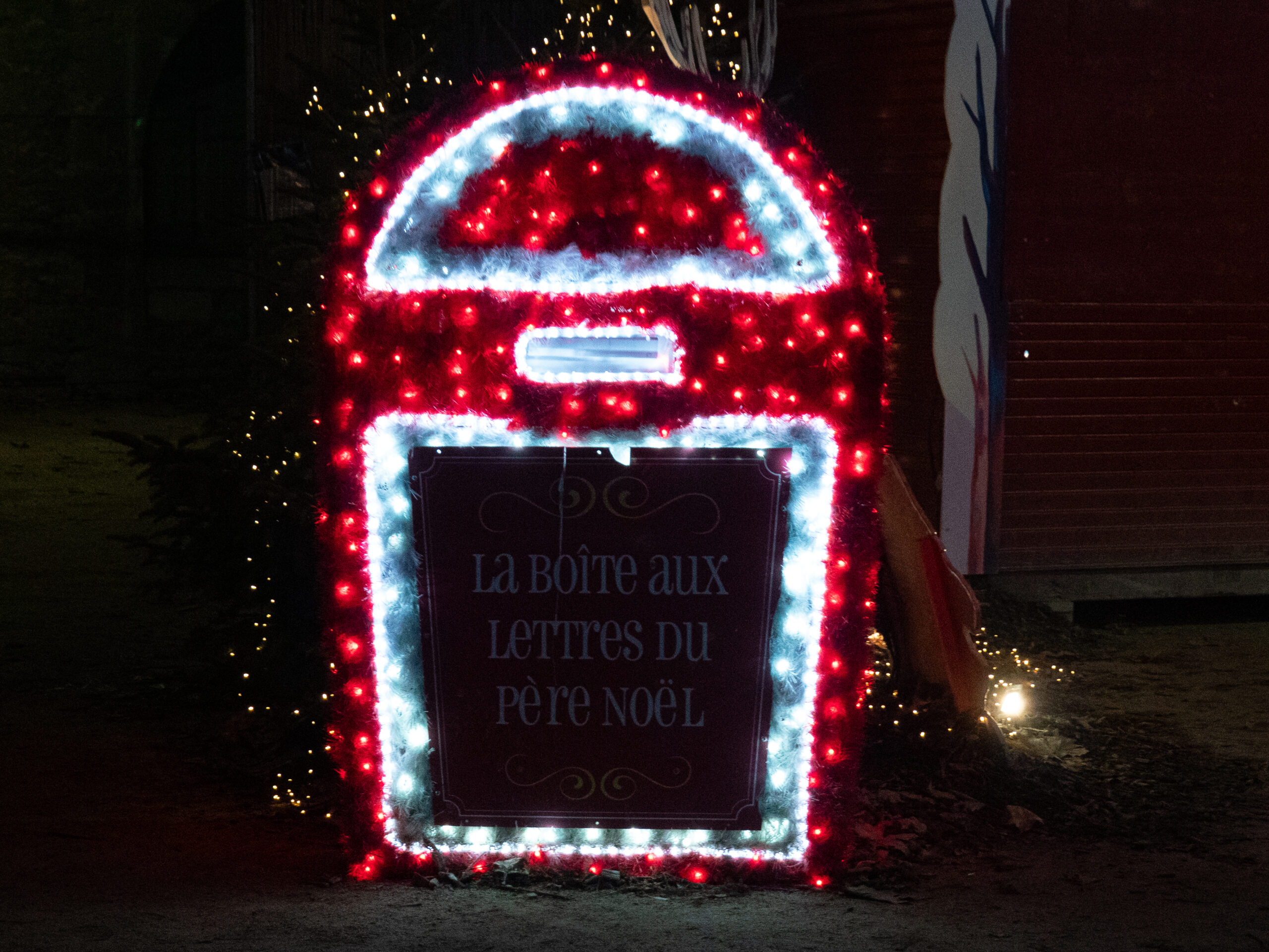 Enseigne lumineuse décorée en blanc et rouge, sur laquelle on peut lire la boite aux lettres du père noël. On peut y glisser des lettres dans une fente prévue à cet effet