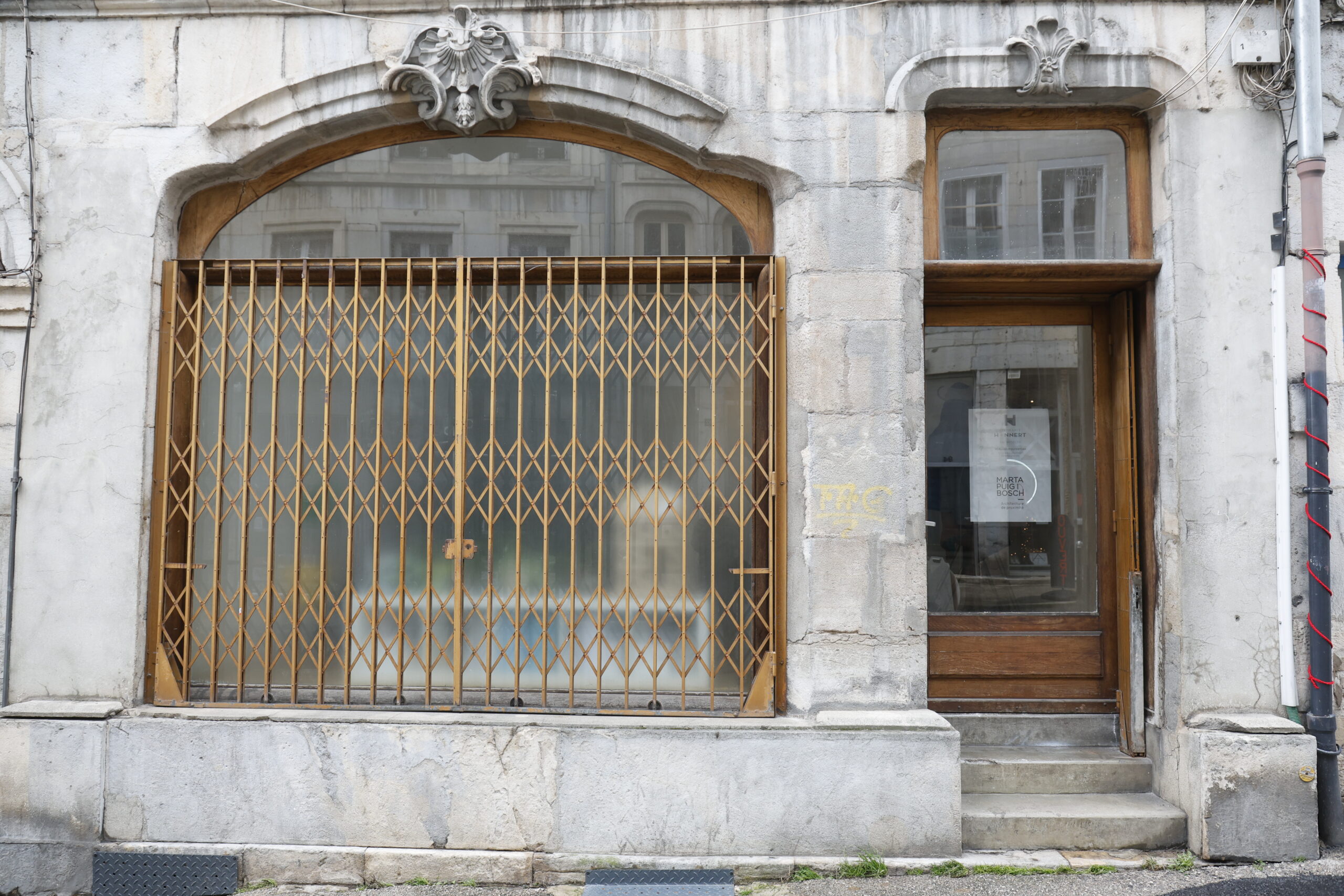 Photo de la devanture de l'architecte Marta Puig i Bosch, fermé, le rideau de fer cuivré tiré