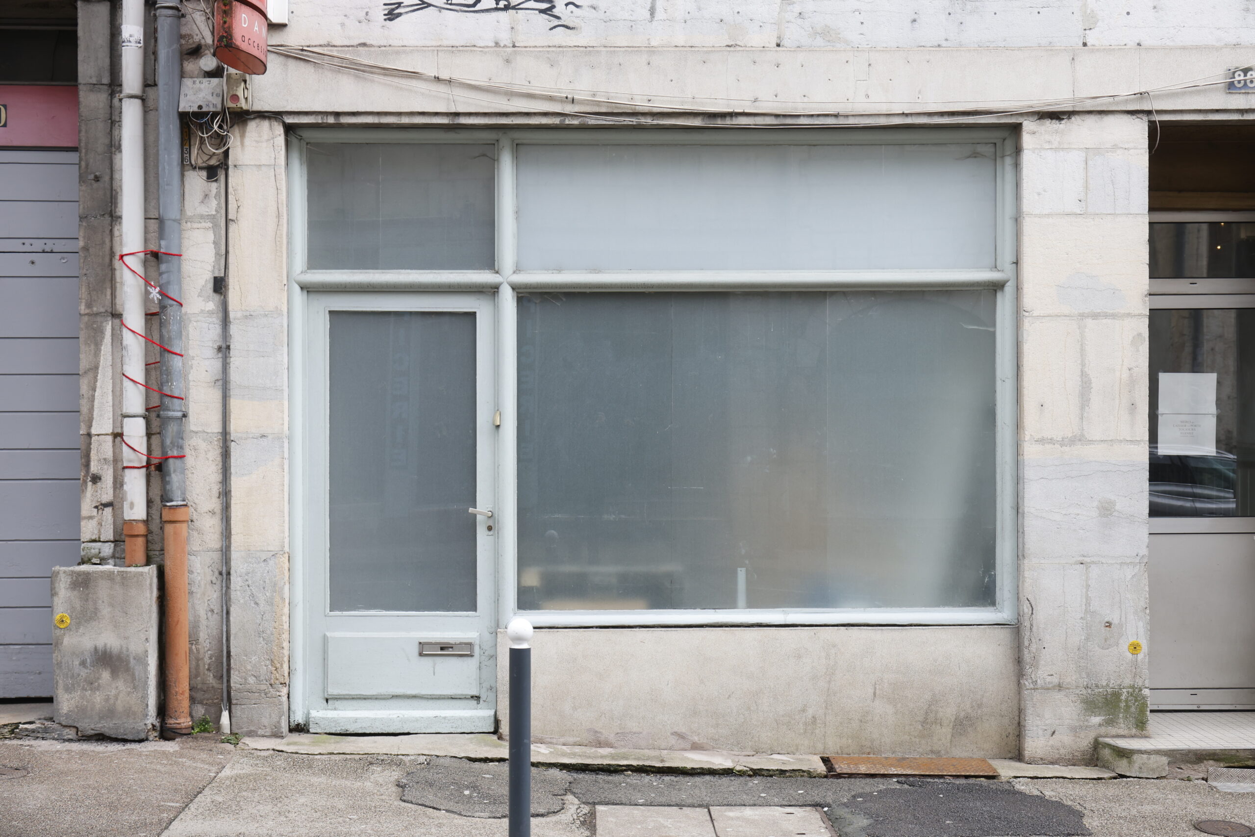 Photo de la devanture d'un commerce inconnu, fermé, les vitres de la porte et de la vitrine recouvertes d'un film semi-opaque