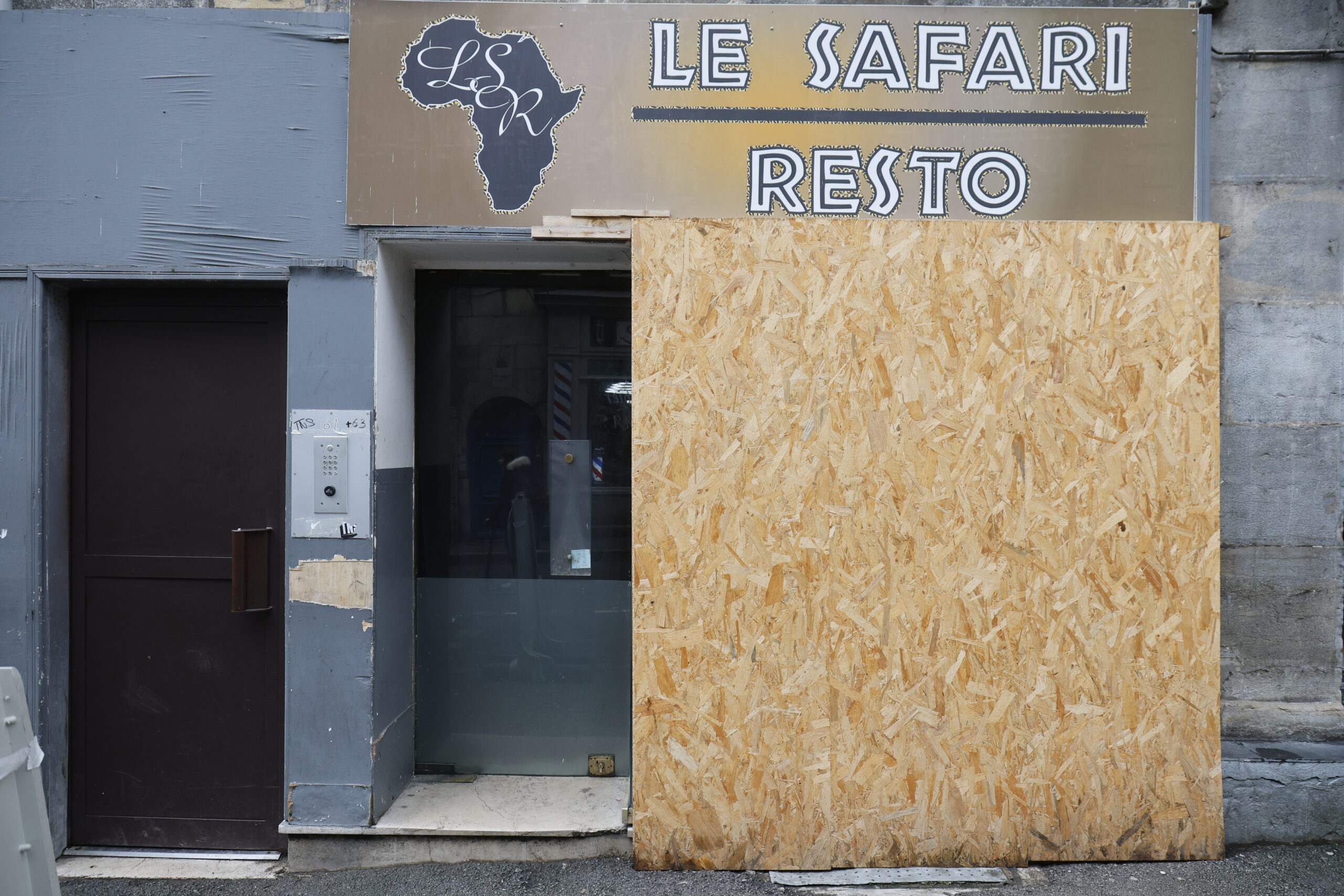 Photo de la devanture du restaurant le Safari Resto, fermé, une plaque de bois aggloméré obstruant la vitrine