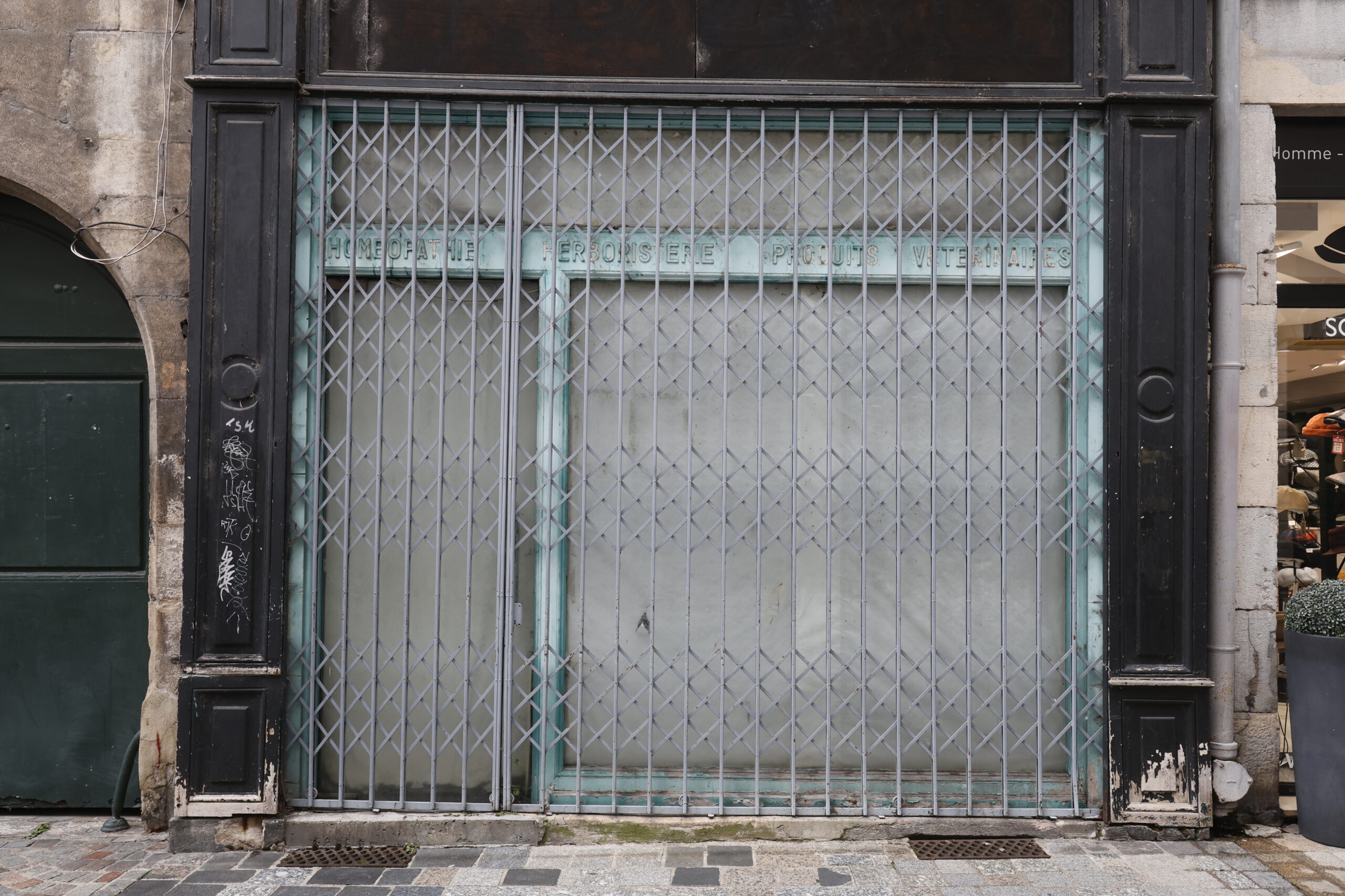 Photo de la devanture d'un commerce inconnu, rideau de fer entièrement tiré, vitrine et porte totalement opacifiée.