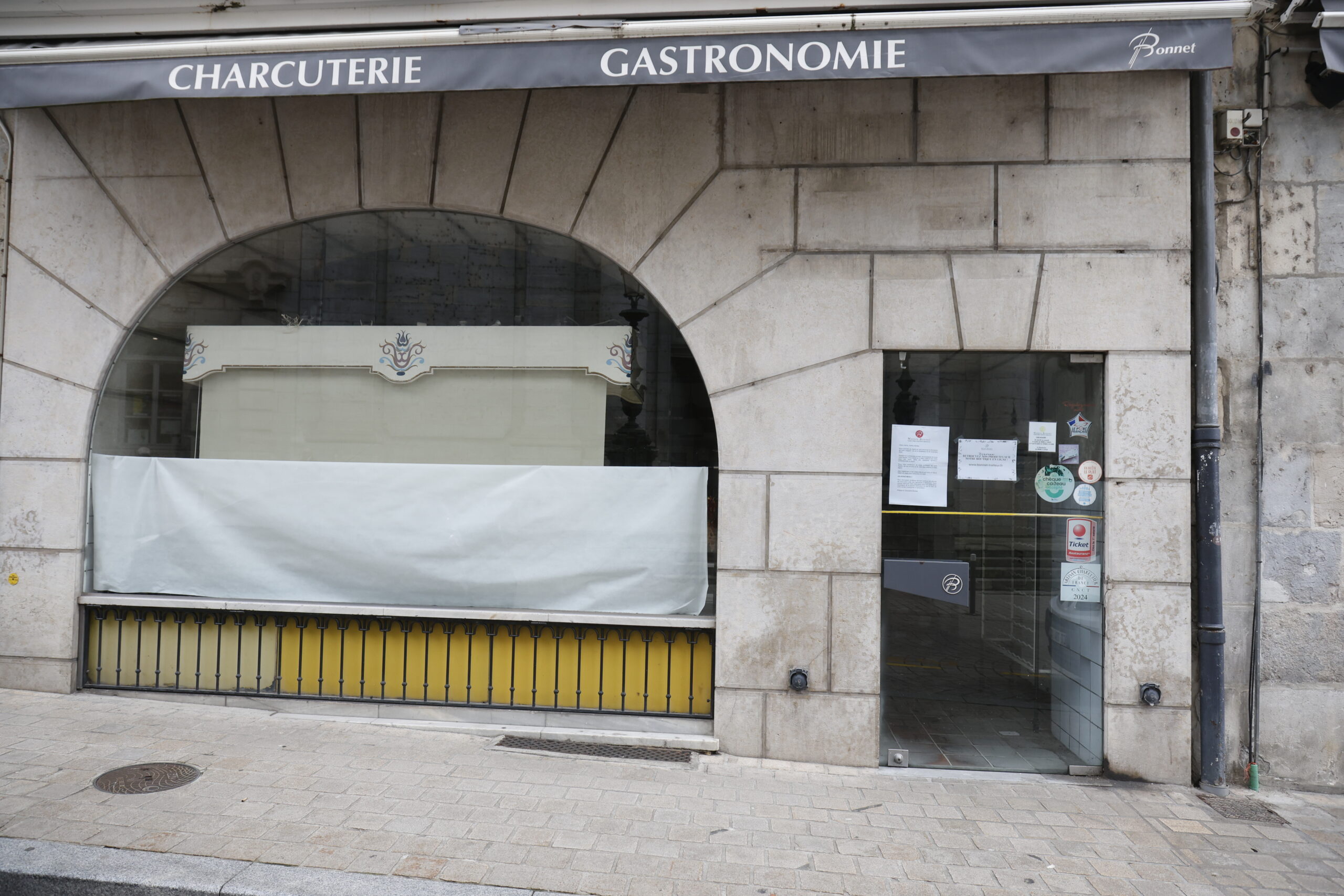 Photo de la devanture d'une boucherie charcuterie, fermée, la vitrine obstruée