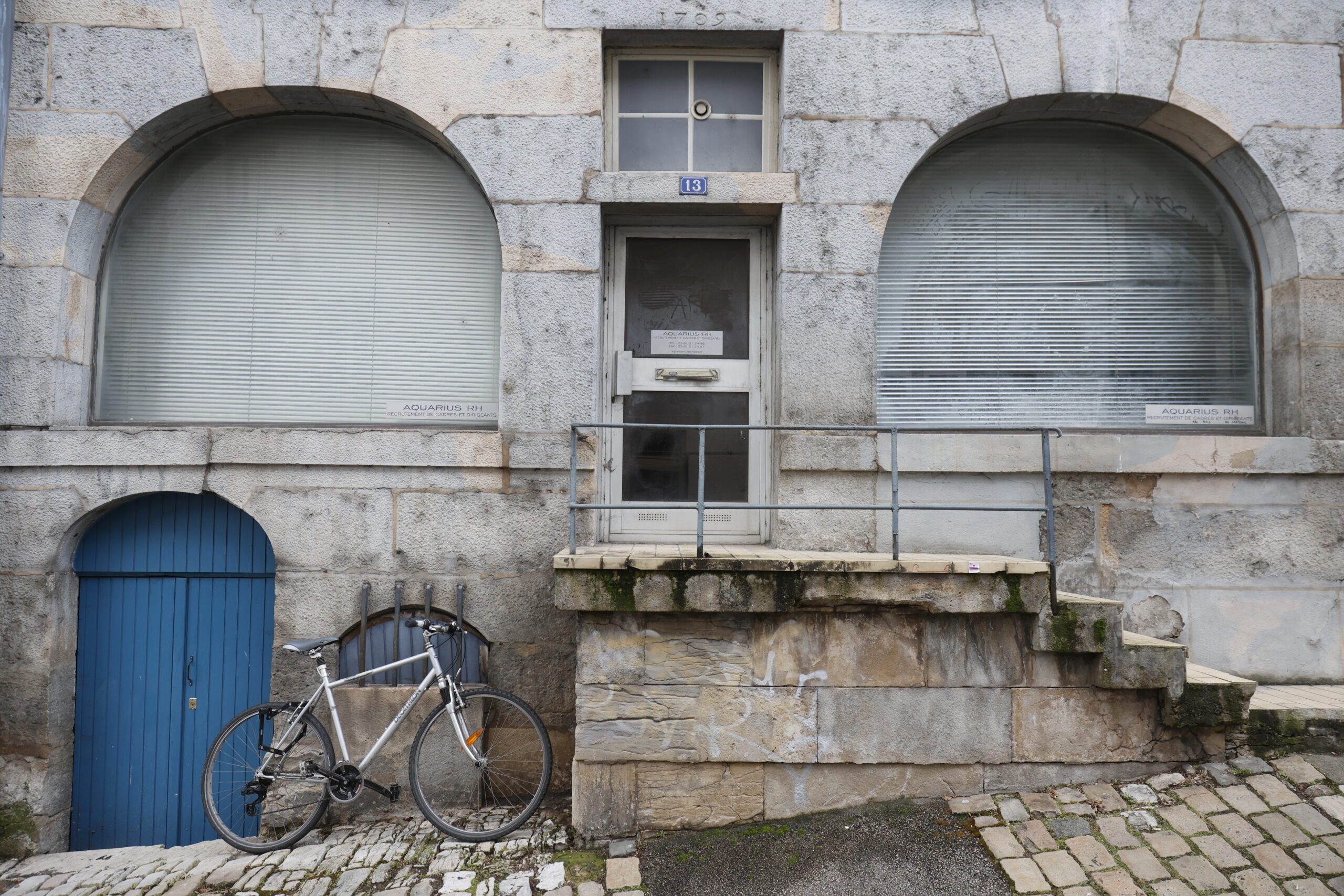 Photo de la devanture d'une boite de recrutement, en haut d'une petite série de marches en pierre, fermée, les fenêtres sous arche de part et d'autre de la porte opacifiées