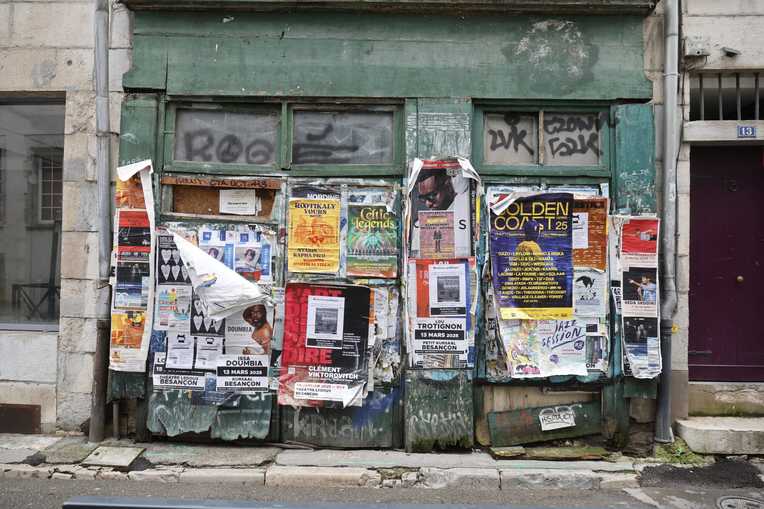 Photo de la devanture d'un commerce tellement recouvert d'affiches qu'on ne voit littéralement plus rien, à part les montants verts autour de la vitrine