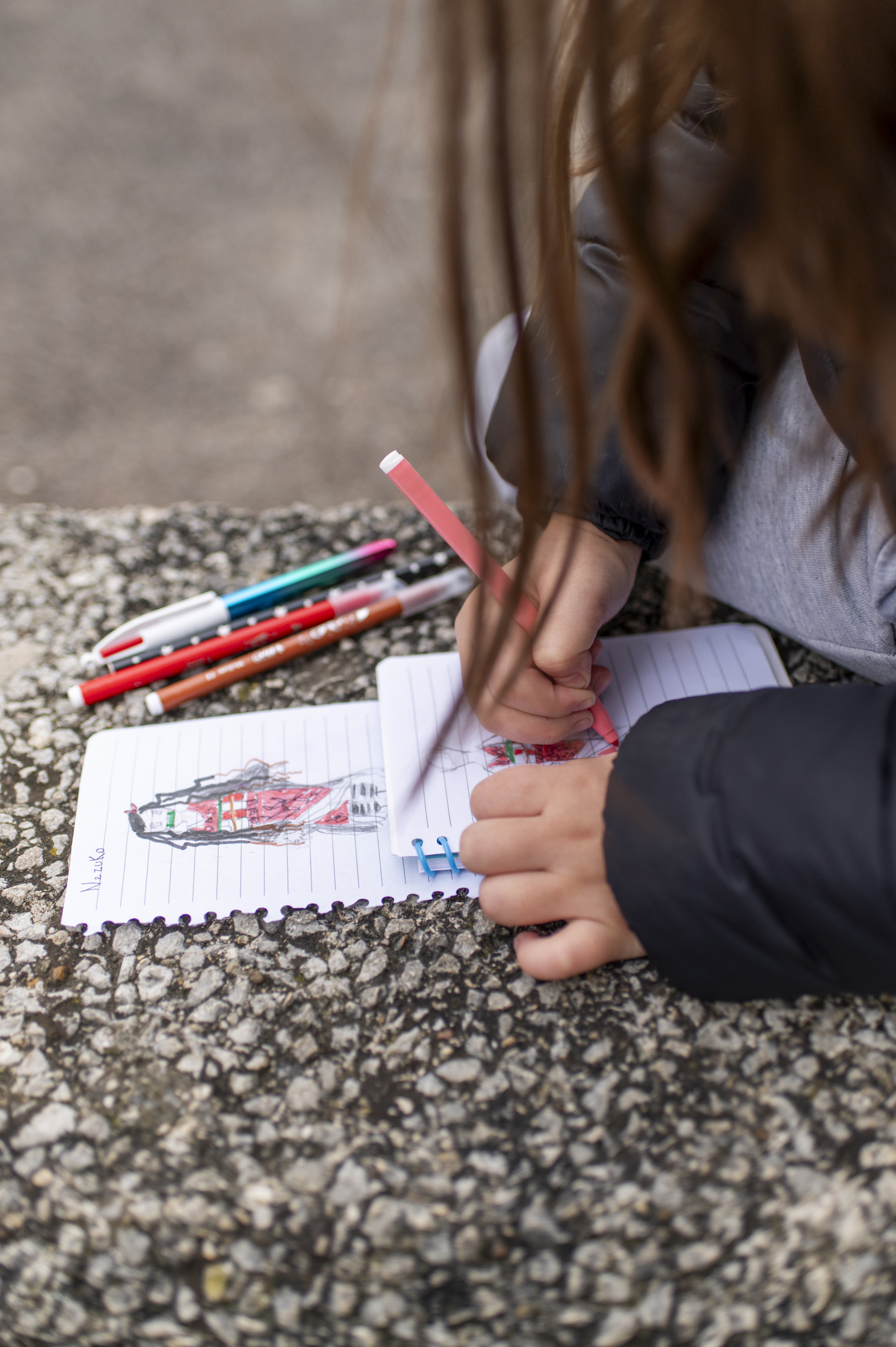 Une enfant dessinant sur un banc